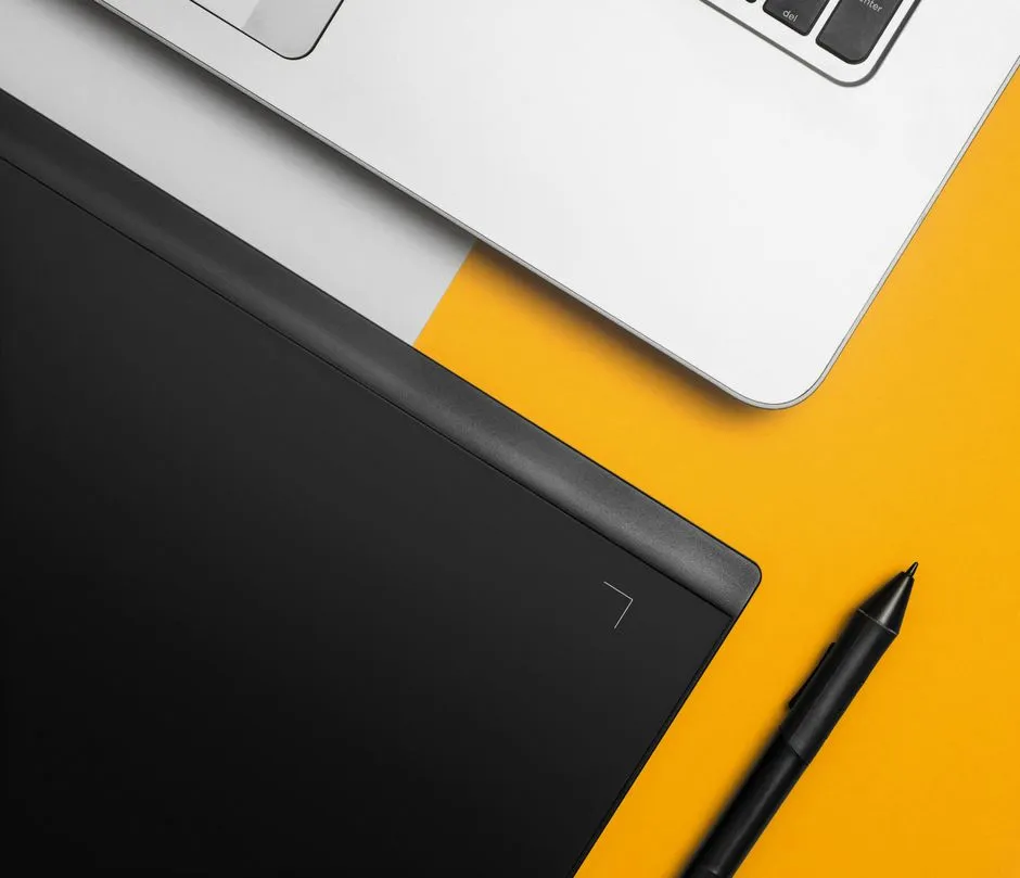 Pen resting on a laptop keyboard next to a notebook, illustrative of the design work behind curating an icon library